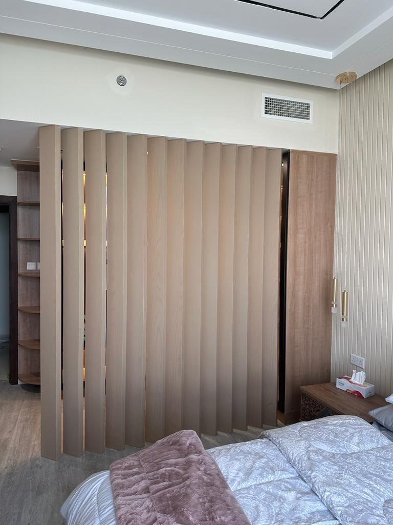 Oak vertical-fin screen between a bed and a closet area