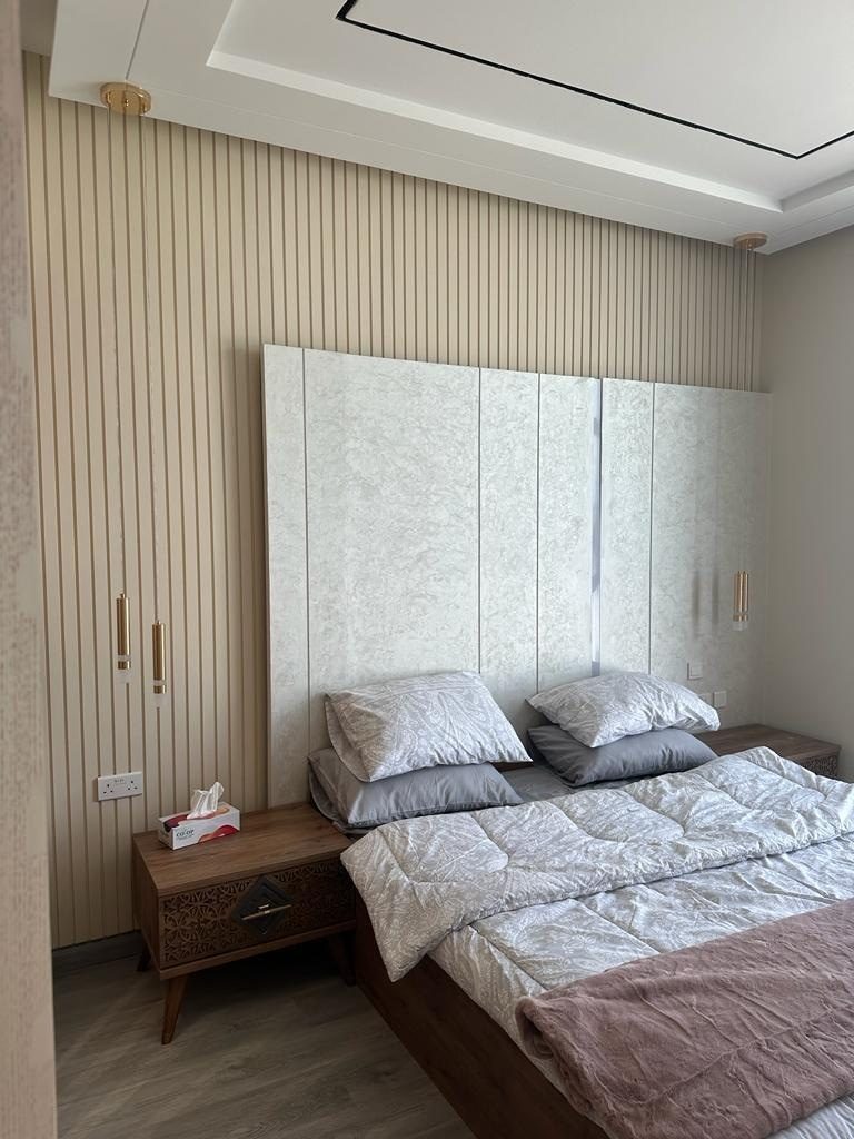Bedroom with a slatted wall and a tall textured panelled headboard