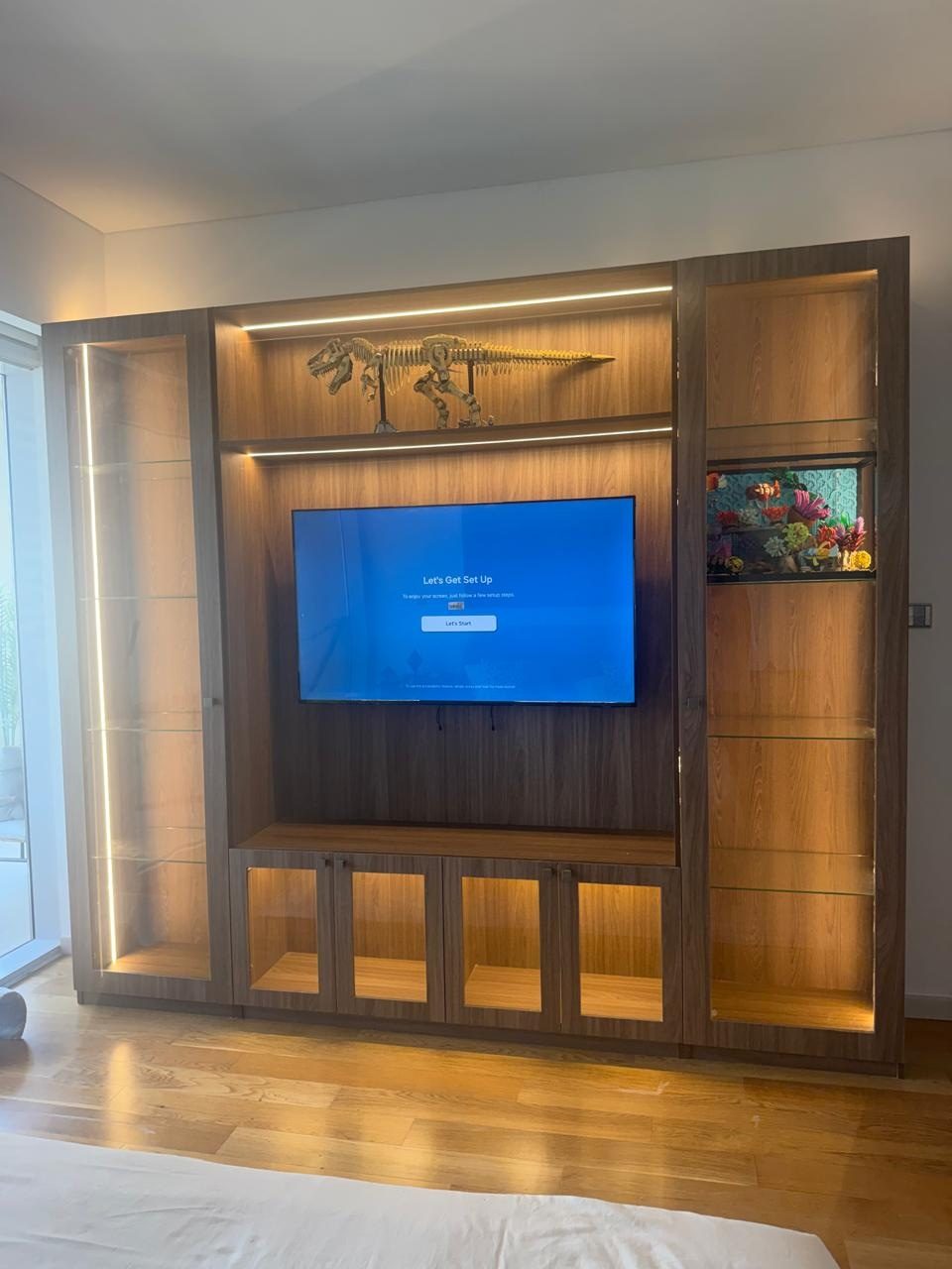 Full-wall walnut TV unit with lit glass display cabinets on both sides